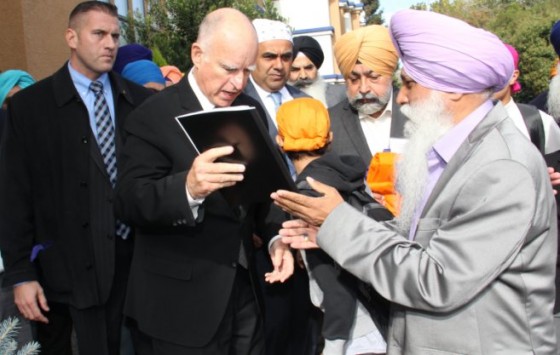 A survivor of the 1984 massacres hands over a copy of Sikh Genocide 1984 Report to Gov. Jerry Brown